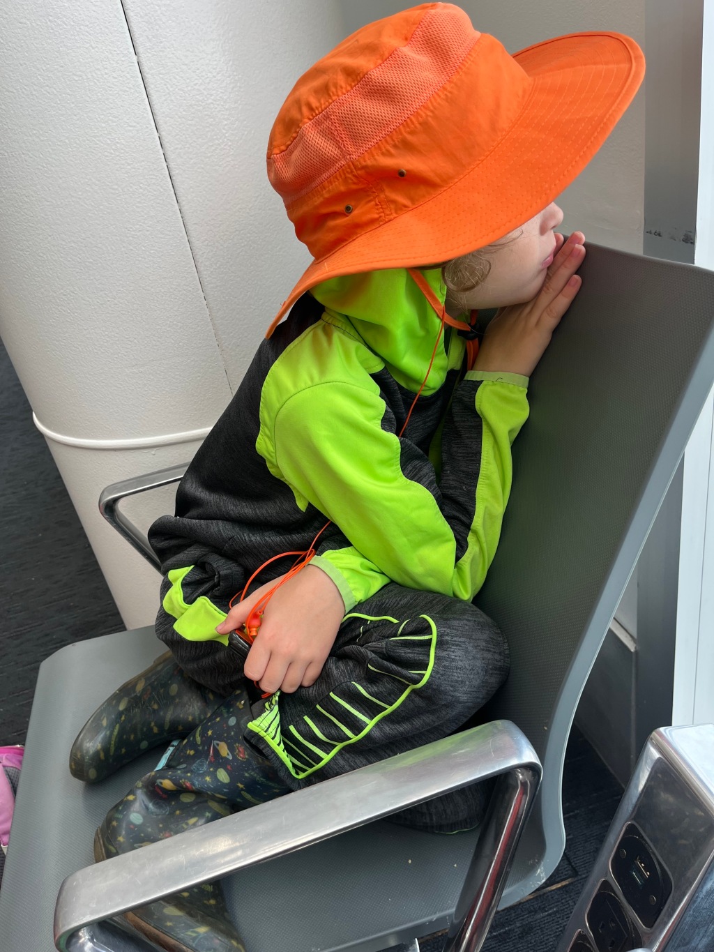seven year old child waiting in airport chair at gate